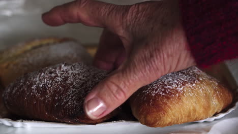 cierra la mano de una mujer con manchas de la edad recogiendo un tradicional pastel napolitano italiano famoso llamado sfogliatella napoletana 4k