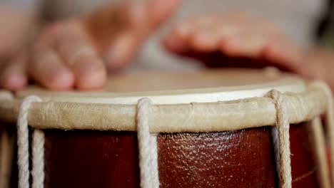 close up of hands of a man playing a drum.