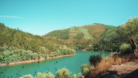 countryside river with boat get away among mountain hills on summertime at sunshine under blue sky in wide open shot 4k