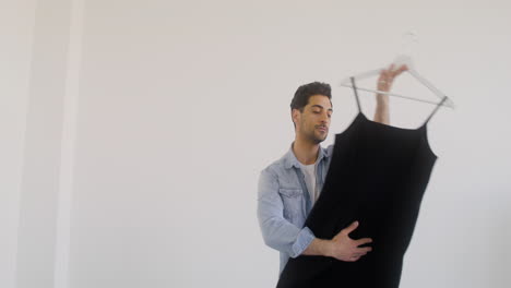 a handsome man is holding a dress while he looks at it