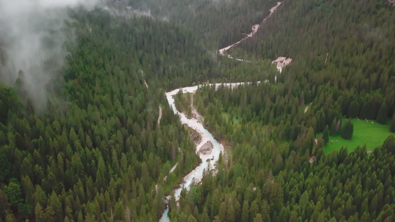 disparo de dron de inclinación rápida hacia abajo de los alpes con nubes bajas volando sobre un río