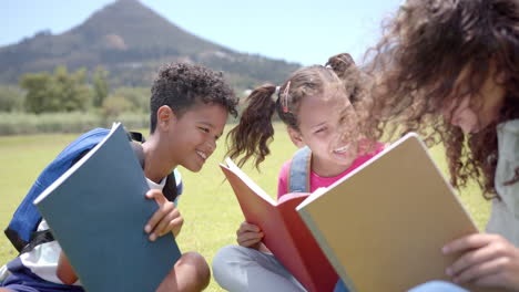 biracial boy and girls are reading books outdoors, with backpacks suggesting a school setting