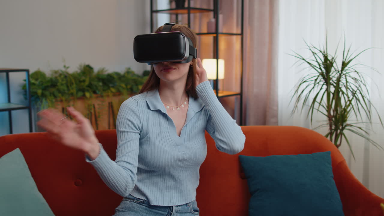 Woman using virtual reality futuristic technology headset to play simulation 3D video game at home