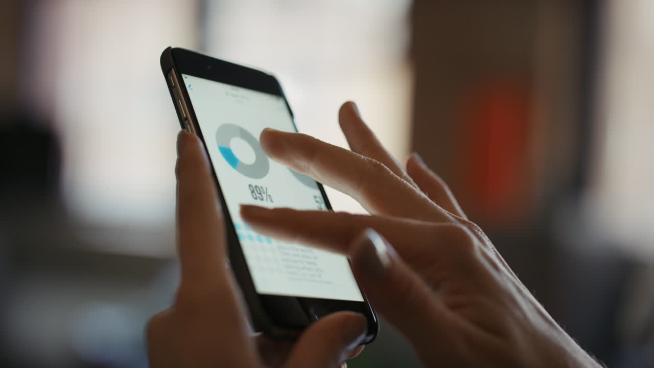 persona que utiliza un teléfono móvil para ver un gráfico circular.