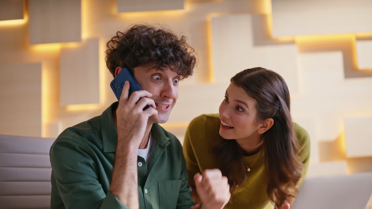 Happy couple celebrating good news on a phone call