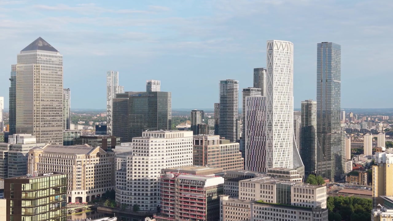 Vista panorâmica do distrito financeiro de Canary Wharf em Londres. Arranha-céus altos se destacam contra um céu azul claro. Arquitetura urbana moderna preenche a cidade vibrante durante o dia.
