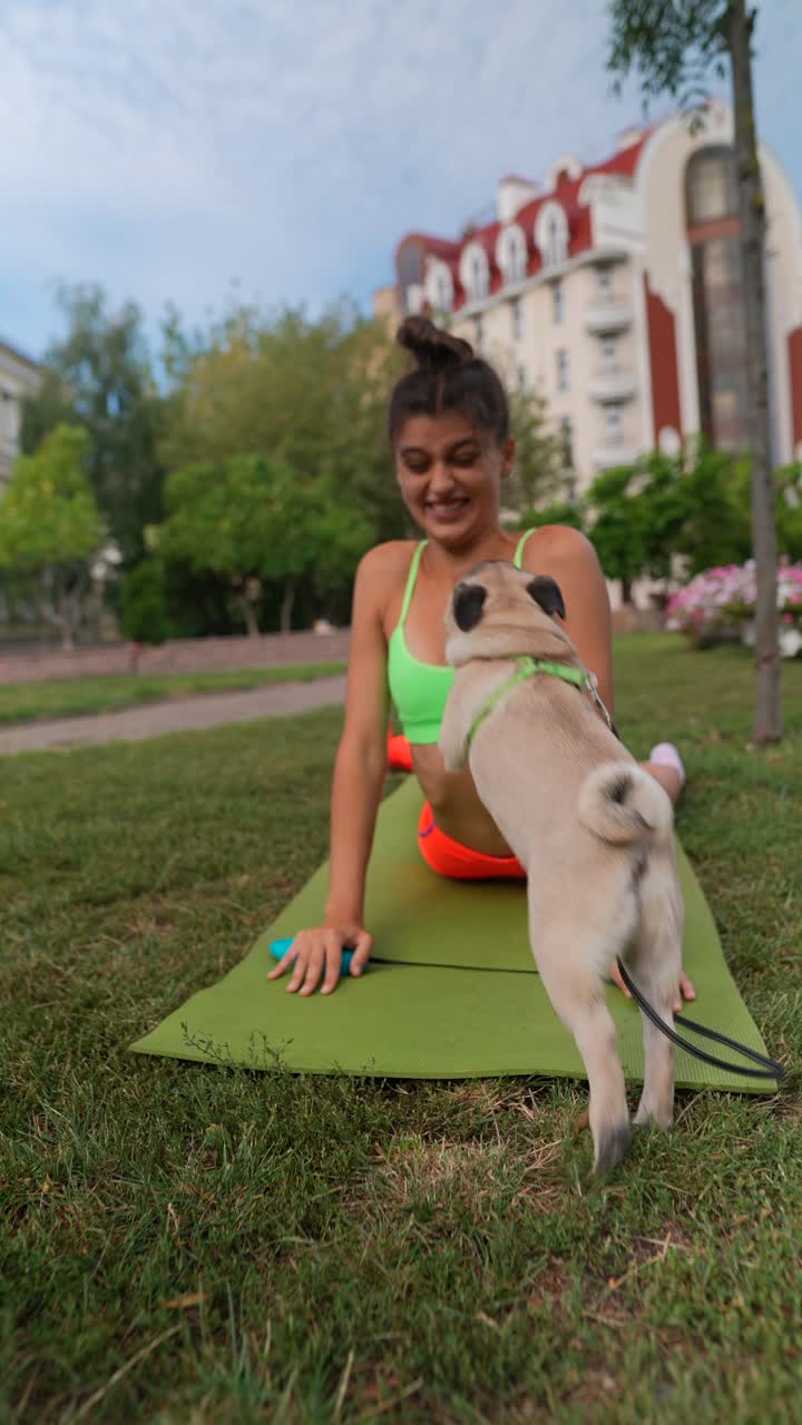 mujer haciendo yoga en un parque con su perro