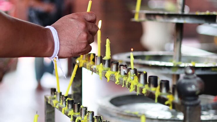 Person lighting candles in a temple setting