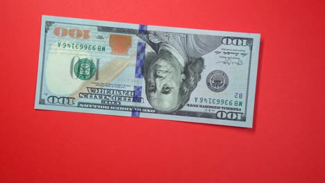 one hundred dollars fast spinning on a rotating red background.