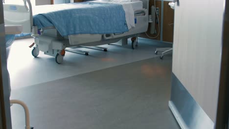 tilt up through a doorway into an empty hospital room, revealing an empty hospital bed