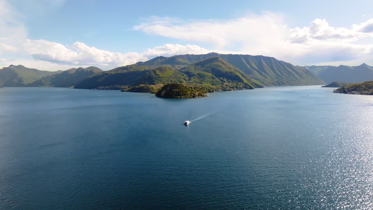 Aerial drone view of a boat on Lake Como, Italy surrounded by mountains