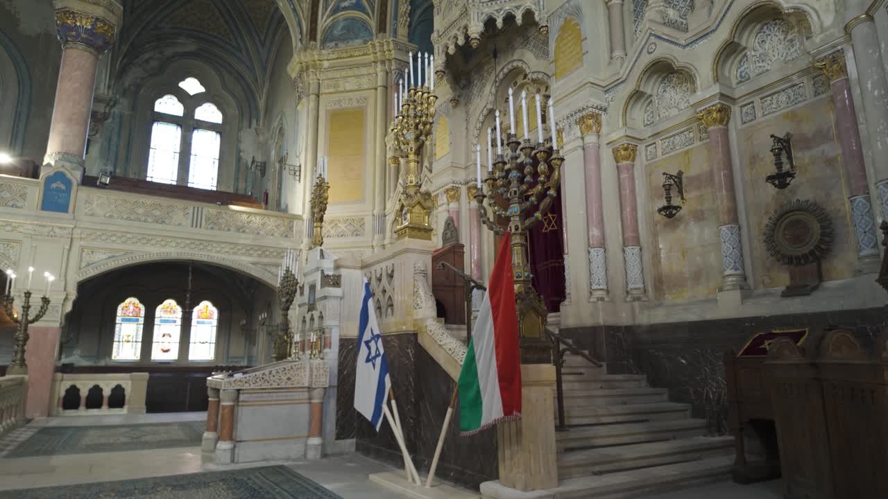 Pan-down view of Szeged Synagogue’s altar, highlighting ornate design and cultural significance with Israeli and Hungarian flags displayed