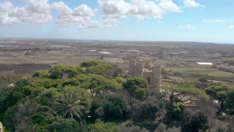 disparo de dron que revela una capilla y un castillo en la cima de una colina rodeada de campo