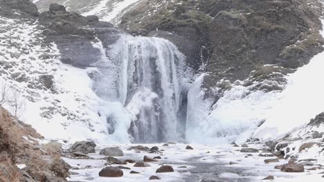 catarata de helgufoss con nieve que cae y cubierta de hielo