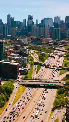 Lively picturesque picture of the city at sunny daytime. Crazy traffic along the multi-lane roads. Aerial perspective. Vertical video