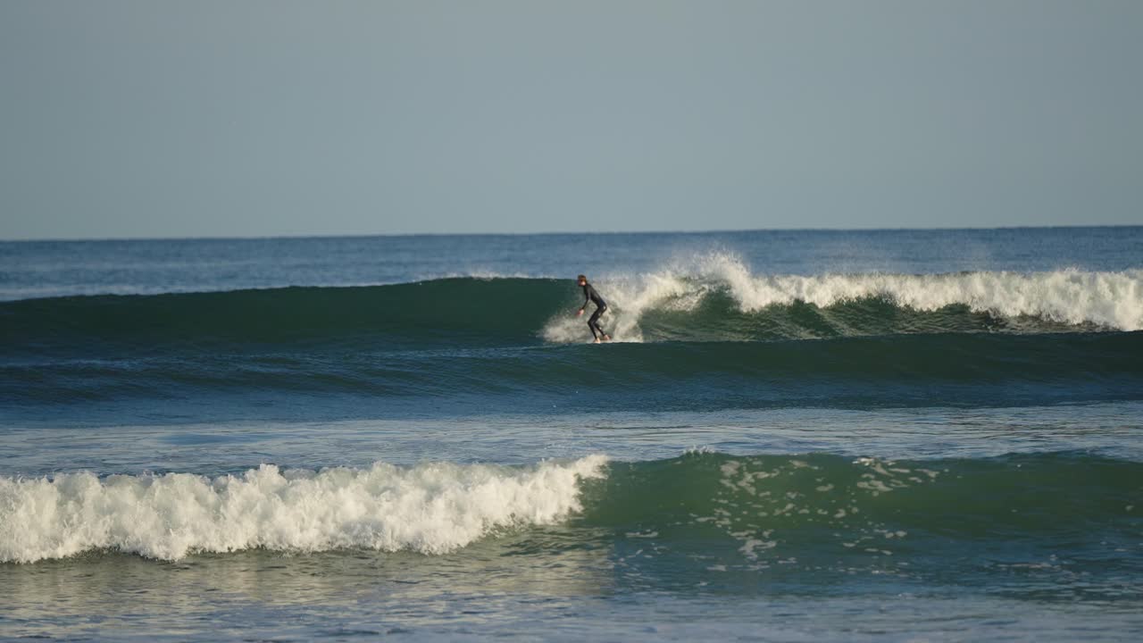 Surfista cavalca un'onda in muta su una tavola corta.