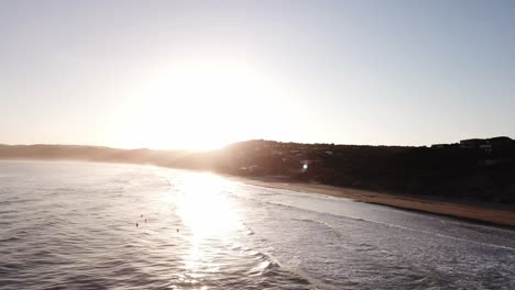 Antena-De-Drones-Durante-La-Puesta-De-Sol-En-La-Playa-Con-Surfistas-Saltando-Sobre-Las-Olas