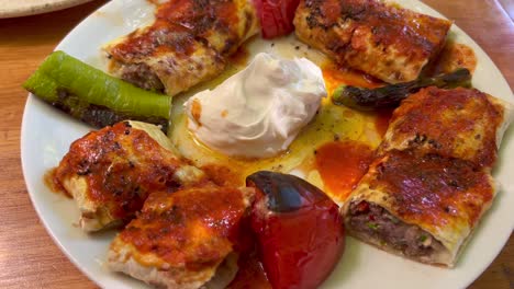 Plato-Tradicional-Turco-De-Carne-Gozleme-Con-Crema-Agria,-Delicioso-Panqueque-Relleno-De-Ternera-Con-Tomates-Y-Pimientos-Asados,-Comida-Auténtica-En-Un-Plato-En-Pavo-De-Bodrum,-Tiro-De-4k