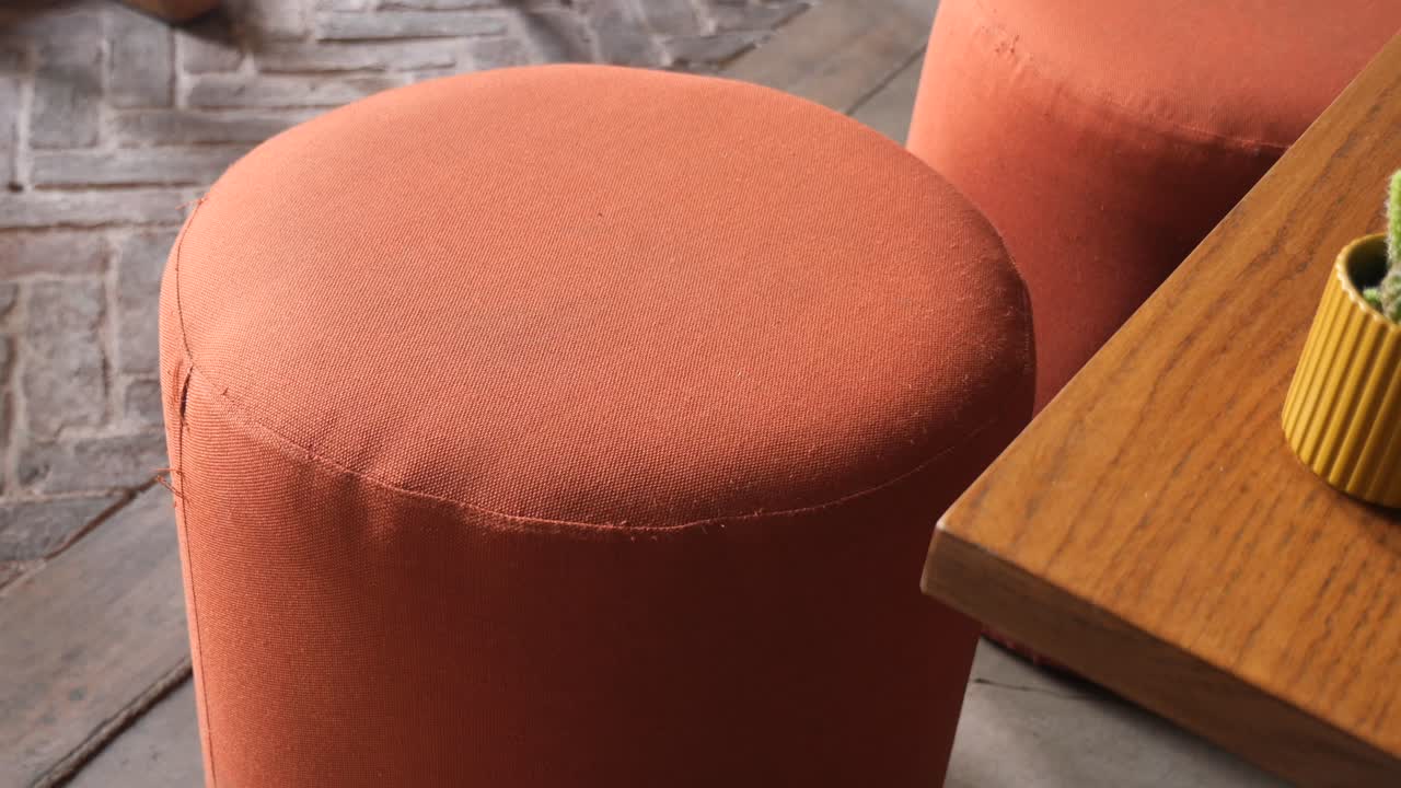 Close-up of orange stools and a table with a cactus