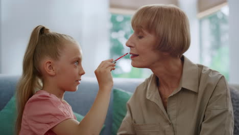 abuela y una niña linda jugando con maquillaje. familia divirtiéndose en el interior