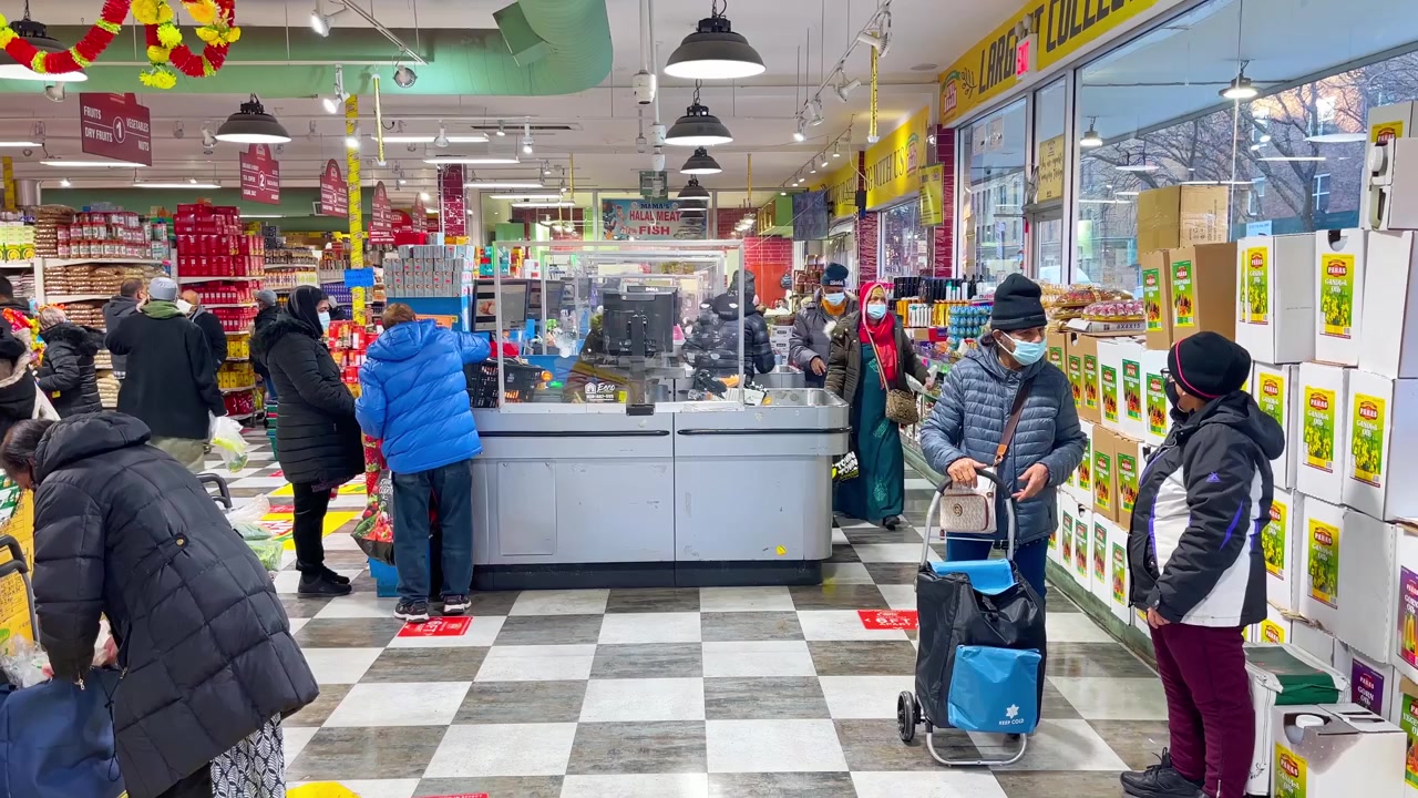 New York, USA, 9 Maret 2022: Interior Pasar Produk Segar yang Luas dengan Pajangan Buah Naga. Interior pasar produk segar yang luas dengan buah naga, kesemek, pembeli, lampu gantung, dan papan nama