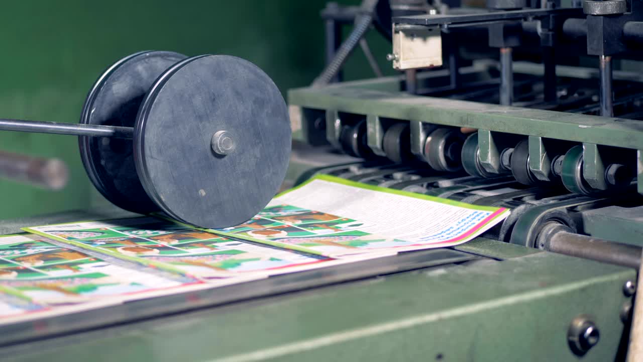 인쇄 된 잡지 들 은 컨베이어 벨트 에 의해 어지고 그 다음 에 롤링 프레스  에 들어간다