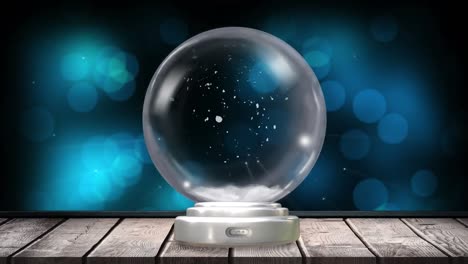 animation of christmas snow globe with snow falling and blue spots on black background