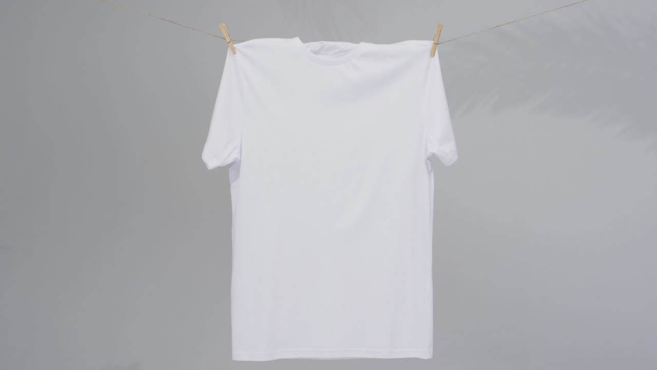 회색 배경에 옷 스 ⁇ 과 복사 공간을 가진  ⁇  티셔츠의 비디오