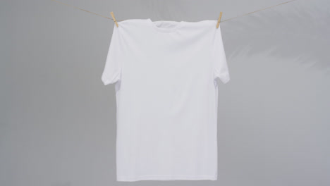 Video-of-white-t-shirt-with-clothes-pegs-and-copy-space-on-grey-background