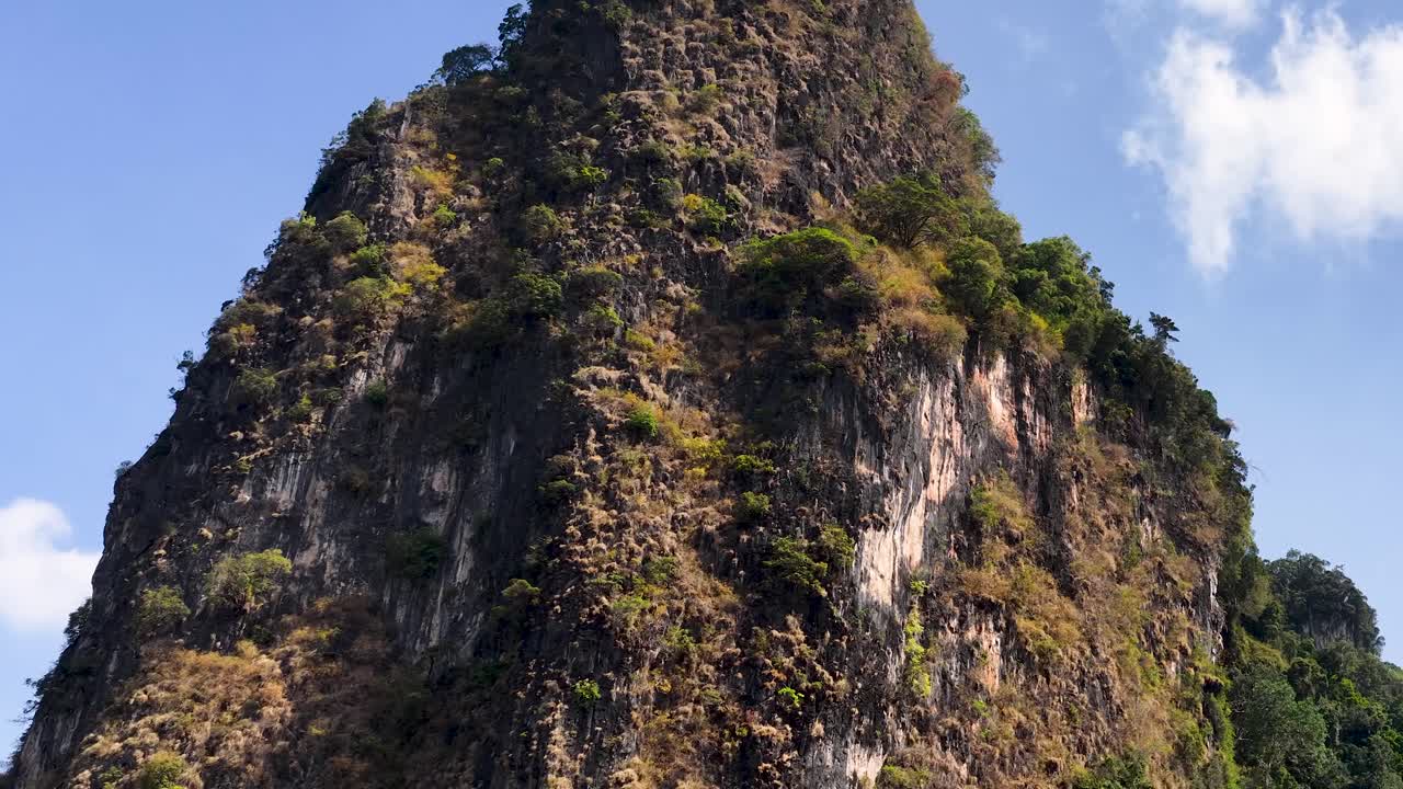 Pergerakan kamera panorama yang lambat merekam gunung karst batu kapur menjulang tinggi di bawah terang cahaya siang.