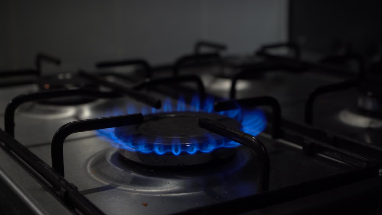 가스레인지의 뜨거운 푸른 불꽃이 점화되고 주황색 폭발로 스퍼터링됩니다.