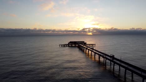 Peaceful-morning-sunrise-over-Deal-pier-Kent-seaside-horizon-aerial-dolly-right