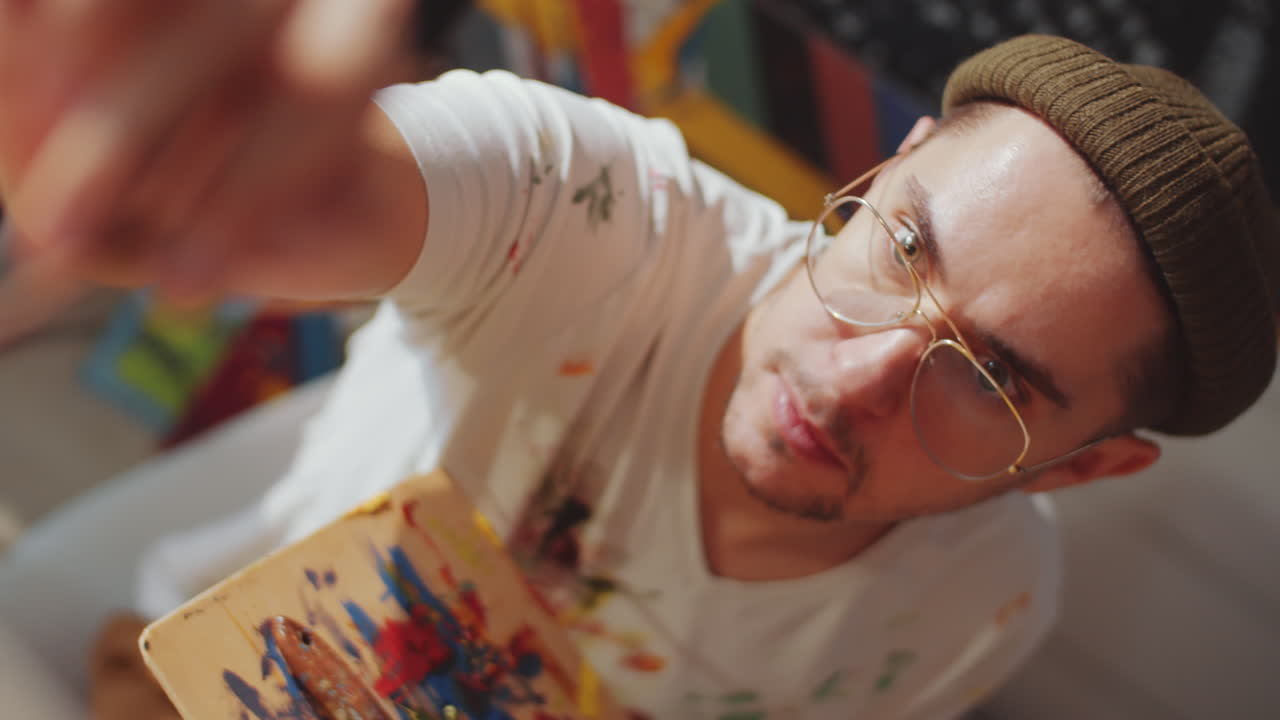 Young Painter Holding Palette and Painting with Brush