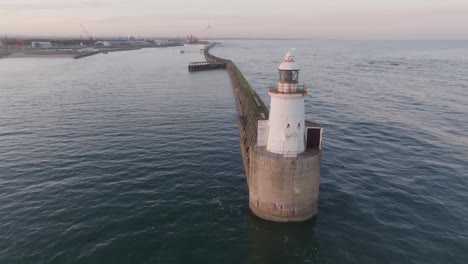 drone clip of rusted blyth lighthouse at the end of long harbour wall, at sunset with calm sea