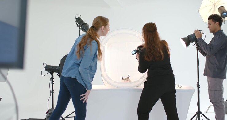Troupe si avvicina al tavolo con una fotocamera e regola lo stroboscopio sopra un set fotografico per uno shooting di prodotto