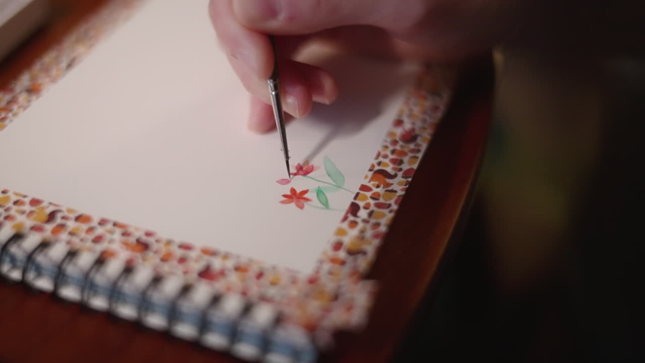 el pintor pinta unas hermosas flores rojas en un bloc de bocetos usando acuarela y pincel