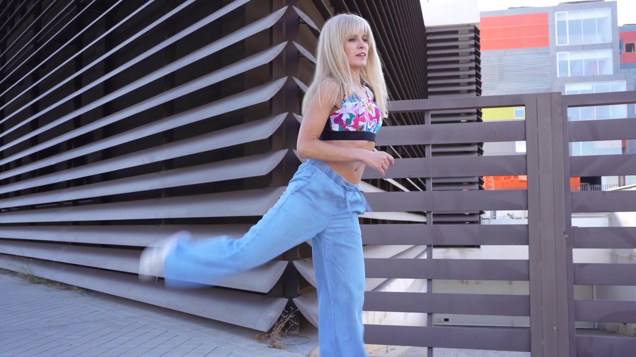 Entuzjastka fitnessu wykonująca ćwiczenia na świeżym powietrzu w pobliżu nowoczesnych budynków architektonicznych.