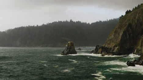 Panorámica-Aérea-Lenta-A-Través-Del-Océano-Pacífico-Rompiendo-Contra-La-Costa-Rocosa-De-Oregon