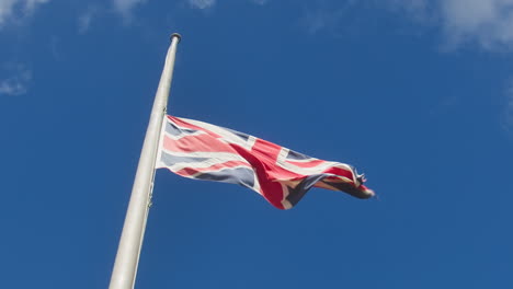 union flag in half mast against blue sky