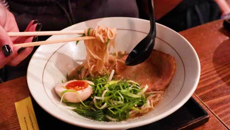 chopsticks lifting noodles from a ramen bowl