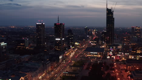 Aerial-view-of-evening-downtown.-Tall-skyscrapers-and-busy-multilane-roads-in-rush-hour.-Overcast-twilight-sky.-Warsaw,-Poland
