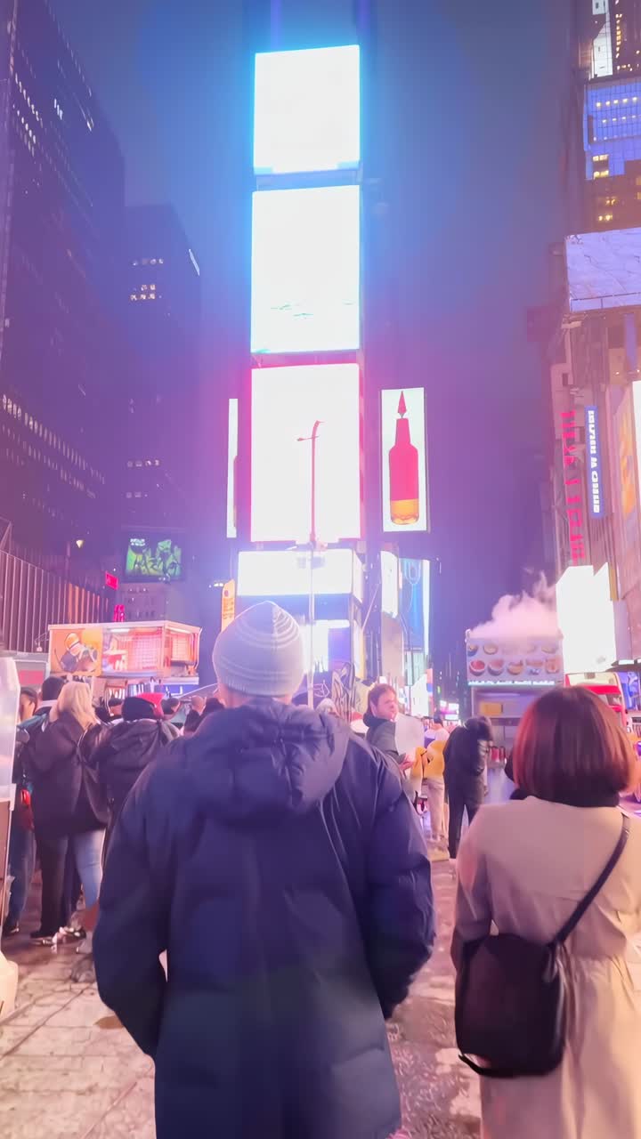 Vivace scena notturna a Times Square con cartelloni luminosi e folle.