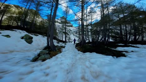 vista trasera de una persona corriendo sobre la nieve hacia el lago helado de lagazzuolo durante la temporada de invierno, valmalenco en italia