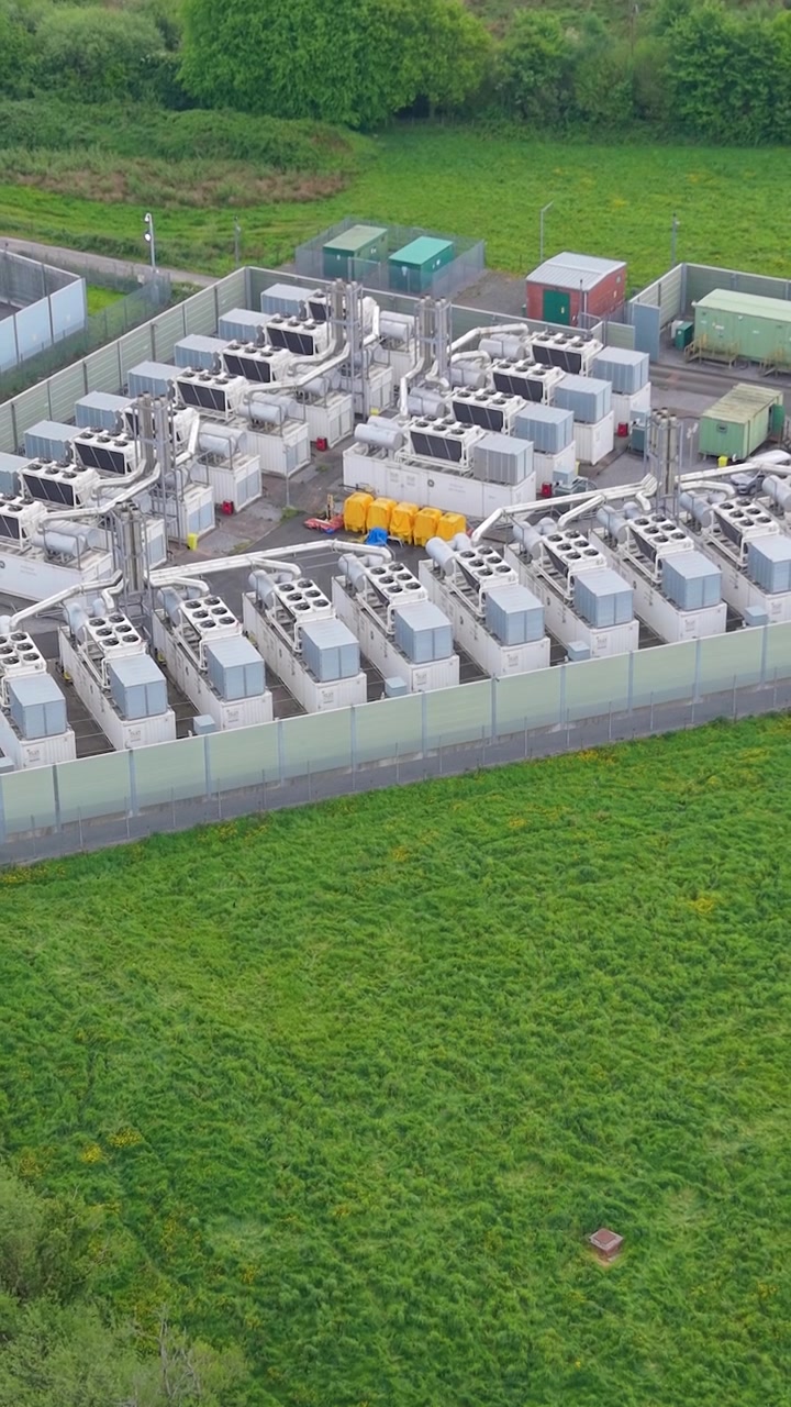 Vertikal video, der trækker sig tilbage, nærbillede af et moderne gasfyret spidsbelastningskraftværk med udstødningsskorstene, generatorer og kølesystemer. Anlægget leverer hurtigreagerende elektricitet til nettet under spidsbelastning. Storbritannien.