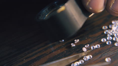 jeweler chooses diamonds with tweezers on table closeup