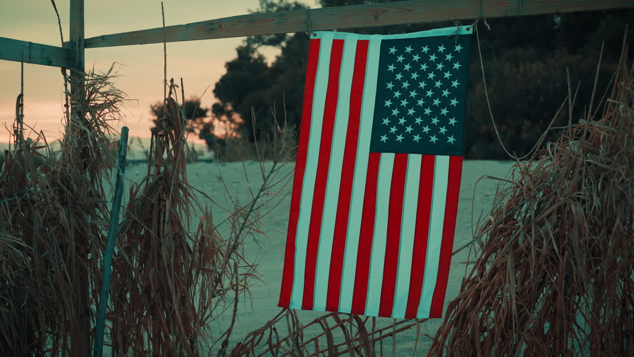 Su una spiaggia di notte, una bandiera americana sventola dolcemente durante il Memorial Day.