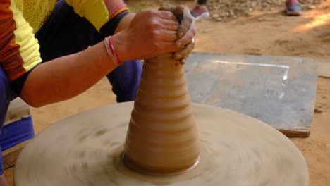 pottery - skilled wet hands of potter shaping the clay on potter wheel. pot, vase throwing. manufacturing traditional handicraft indian bowl, jar, pot, jug. shilpagram, udaipur, rajasthan, india