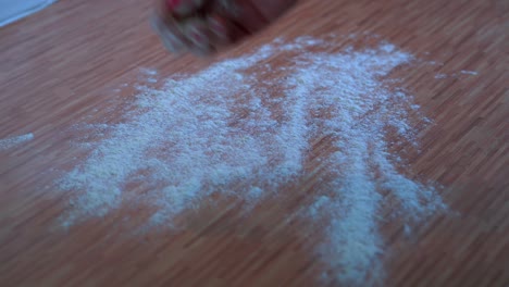 female hand throwing flour on a counter top to knead dough on