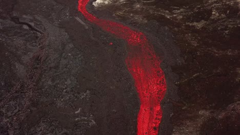 vista aérea sobre un río de lava que fluye a través del valle de meradalir, islandia, saliendo del volcán fagradalsfjall