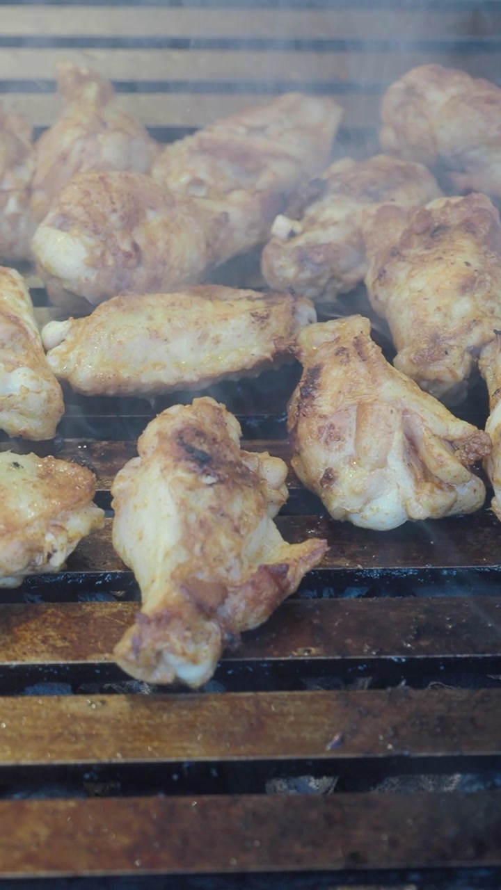 Deliziose ali di pollo e coscette che grigliano su un barbecue caldo